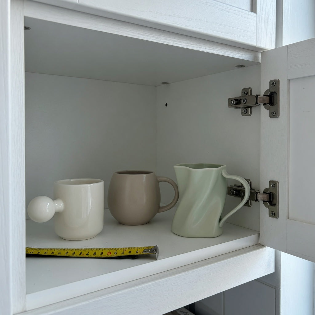 Ceramic coffee mug with handle storage fit guide showing Ball-Handled, Round, and The Flow mug outlines inside a cabinet