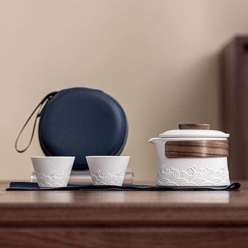 Wave relief ceramic travel tea set with its 230 ml brewer, wood grip band, ceramic infuser, and two matching 40 ml cups.