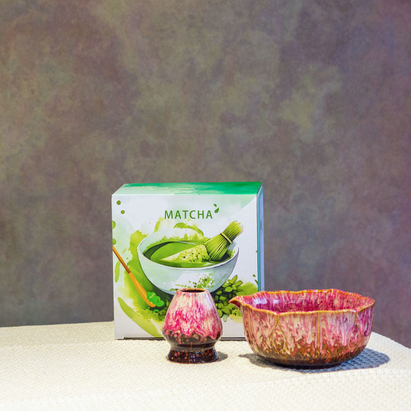 Reactive glaze matcha bowl set with a flower-rimmed ceramic bowl beside its coordinating ceramic whisk holder, the flowing glaze pattern varying across the surface.