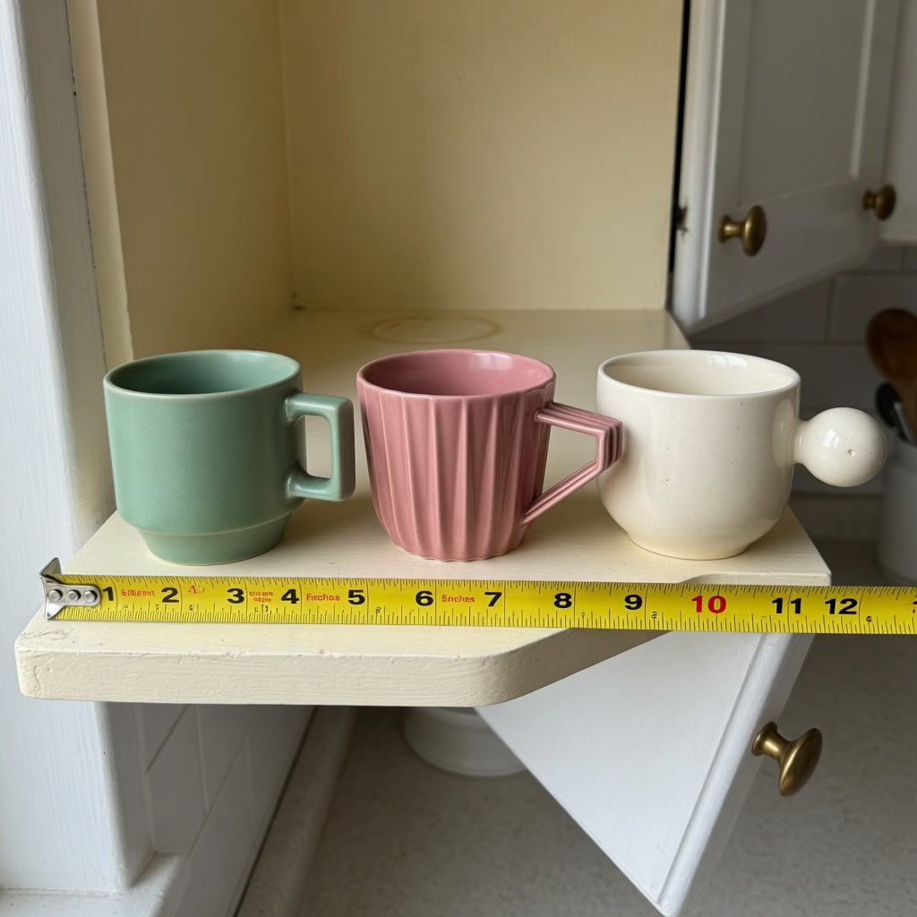 Macchiato cup storage fit guide showing Retro 170 ml, Pleated 200 ml, and Ball Handle 250 ml cups on a measured cabinet shelf