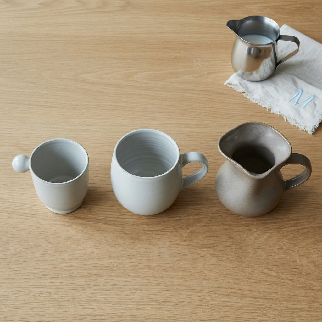 Three mugs side by side on an oak tabletop, comparing matcha mug capacity and opening shapes from 250 ml to 400 ml.