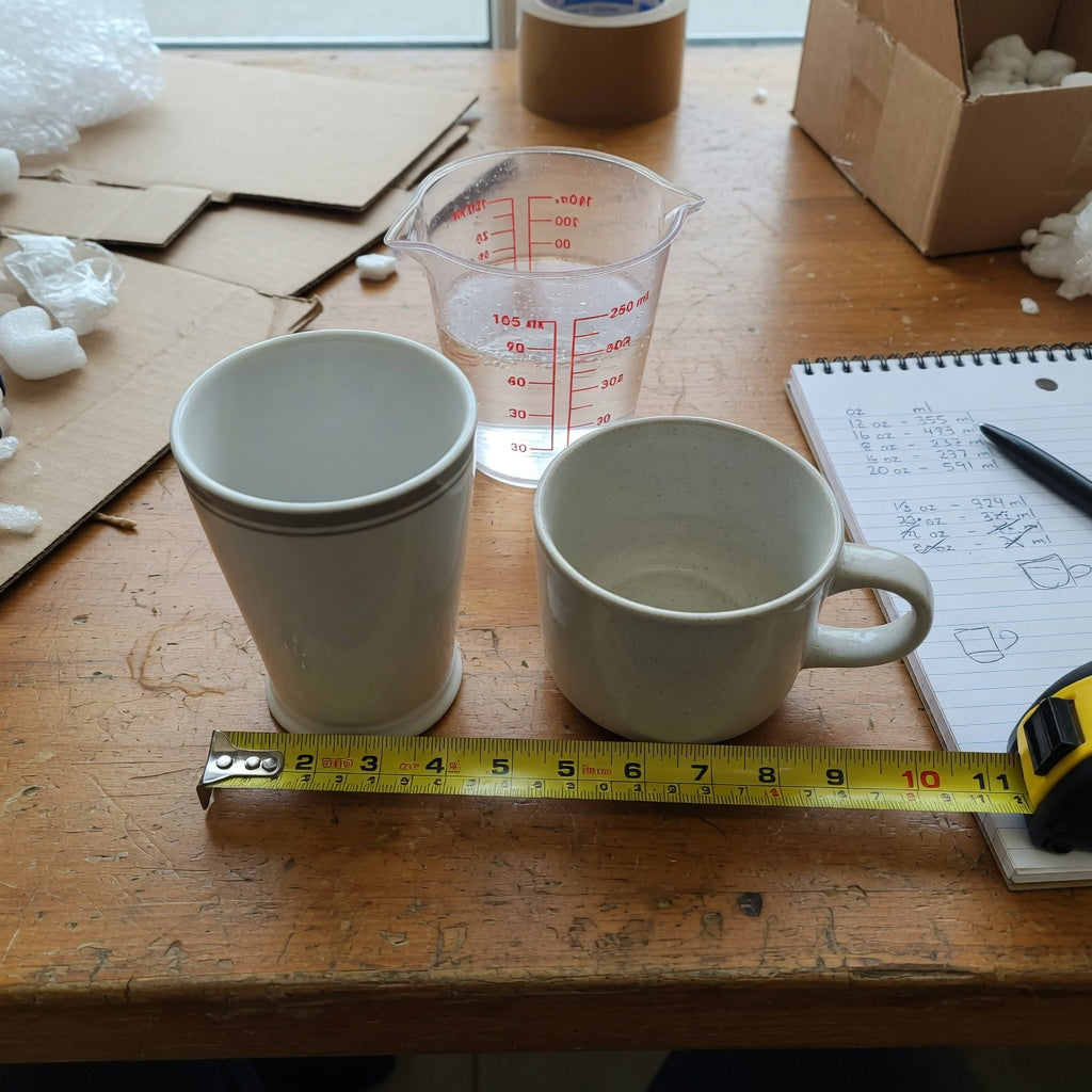 Tall coffee mug vs tea mug size comparison buyer guide with a tall mug, a wider mug, a measuring cup, and a tape measure