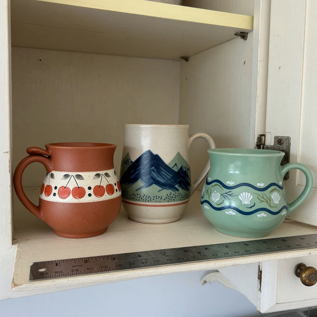 Vintage pottery coffee mugs storage fit guide showing three mug shapes beside a ruler on an open kitchen shelf