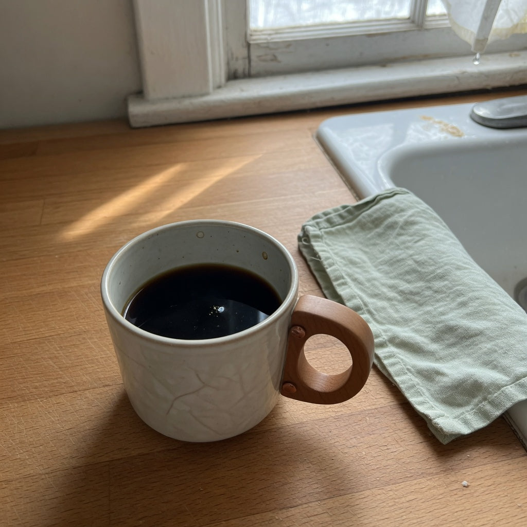 Wooden handle tea mug for coffee lovers on a kitchen counter with coffee poured below the rim
