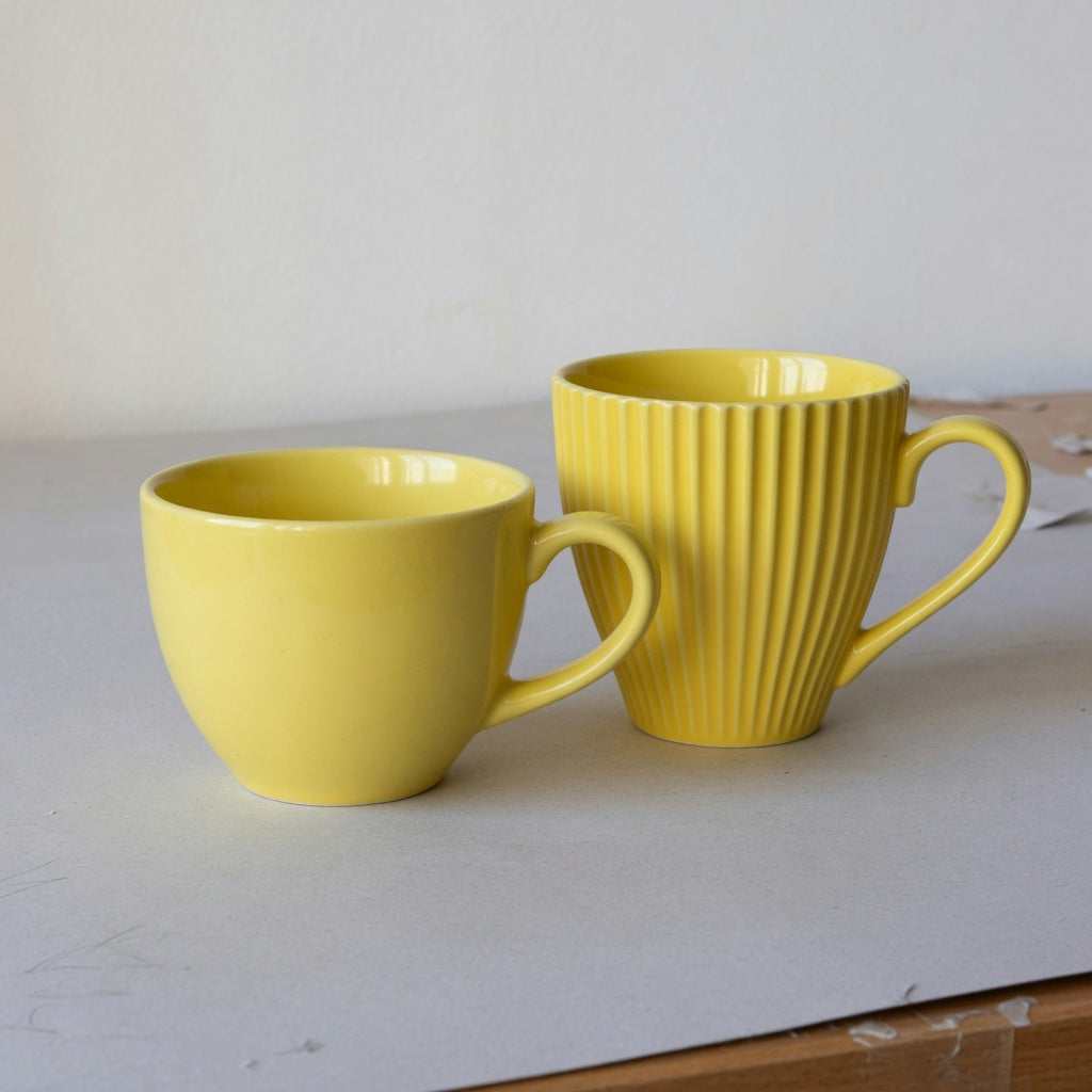 Yellow ceramic coffee mug shape and handle guide comparison showing smooth Retro and ridged Pleated cups with visible loop handles