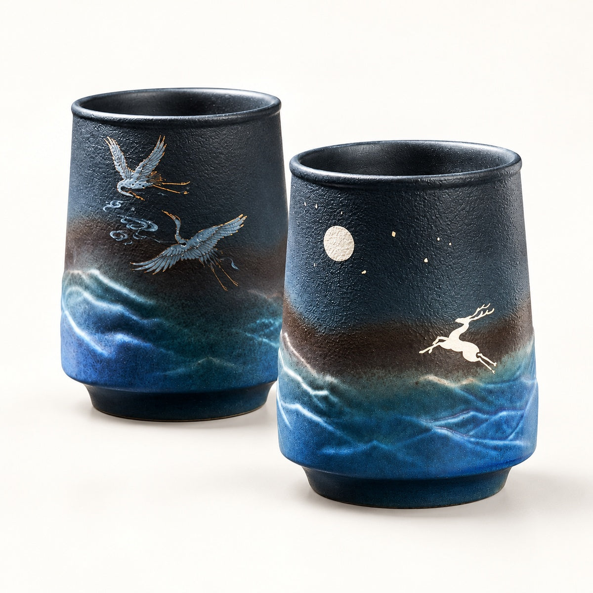 Two deep blue stoneware mugs on a warm white studio background