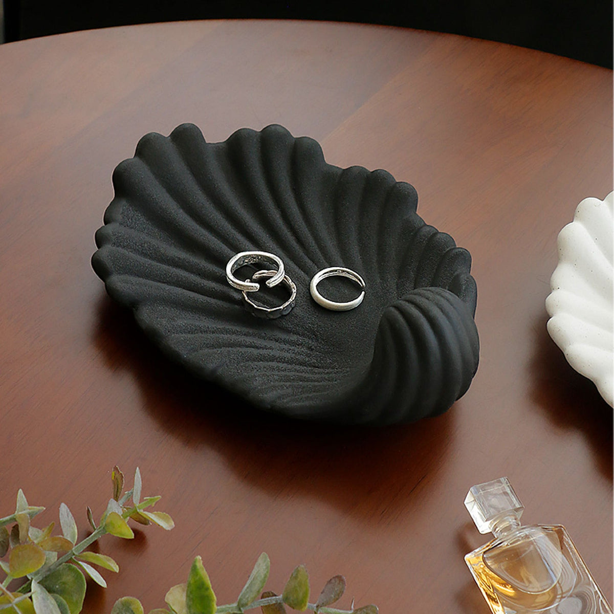 Black shell shaped ceramic jewelry tray displaying rings