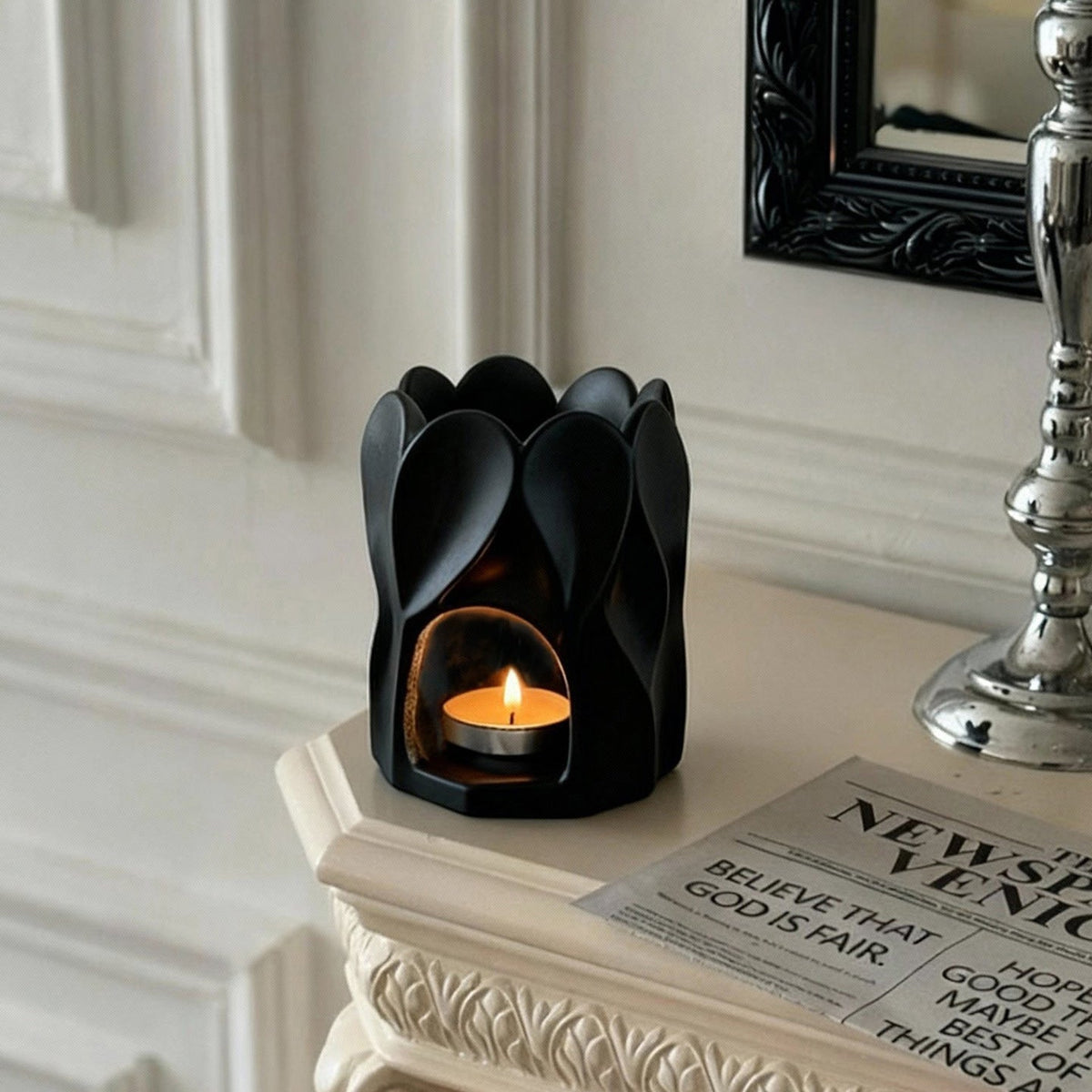 Black petal-shaped ceramic aroma burner on a light mantel
