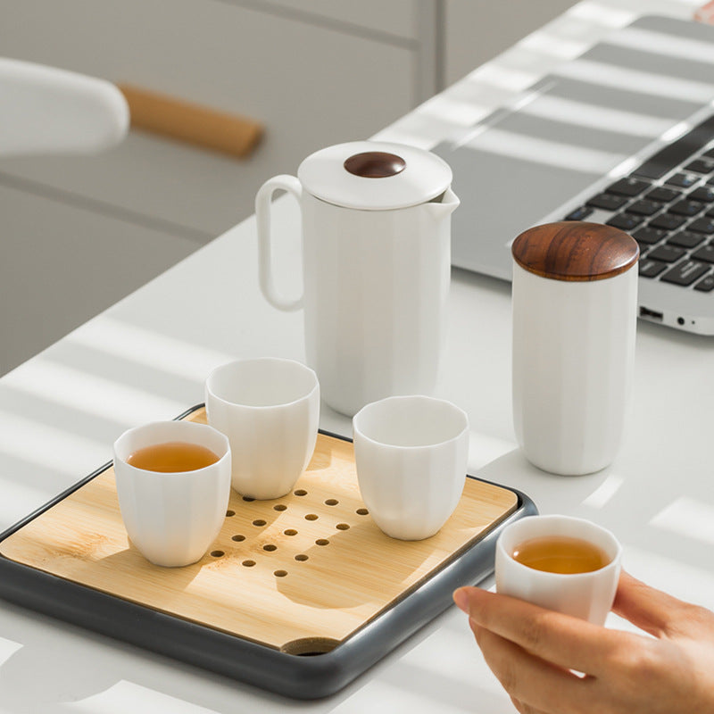 White ceramic four cup tea set with a handled pitcher and tea caddy in use