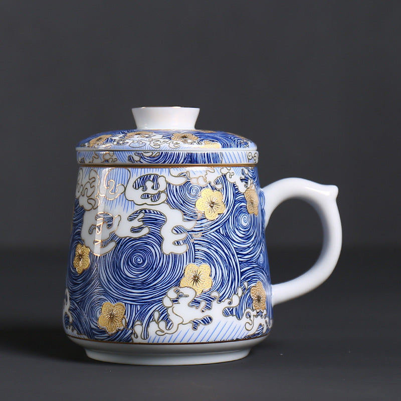Blue and gold ceramic tea infuser mug on a dark background