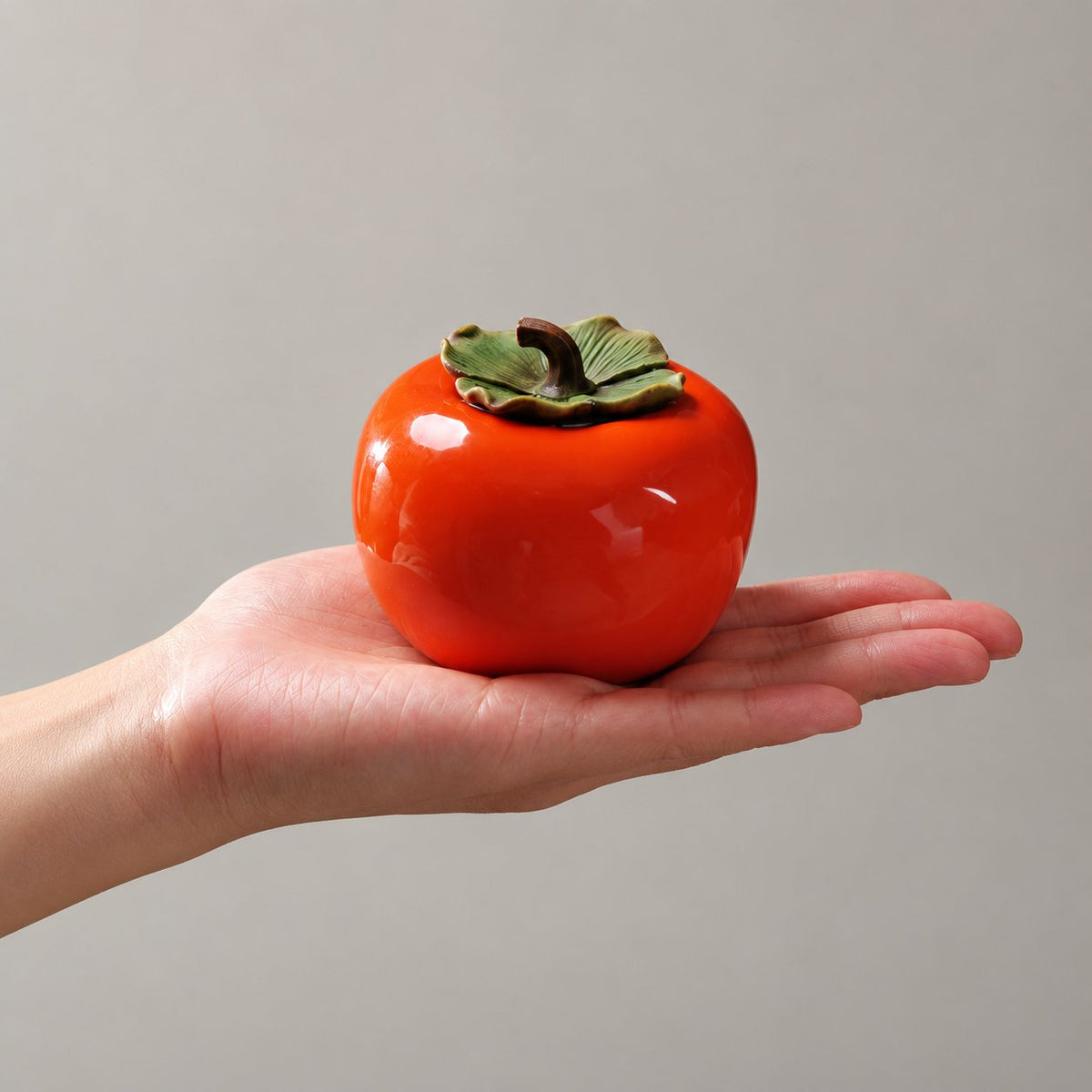 Small persimmon tea jar resting in a hand