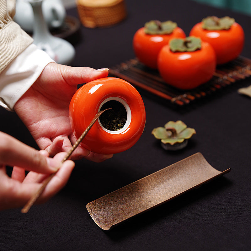 Open persimmon tea jar filled with loose leaf tea