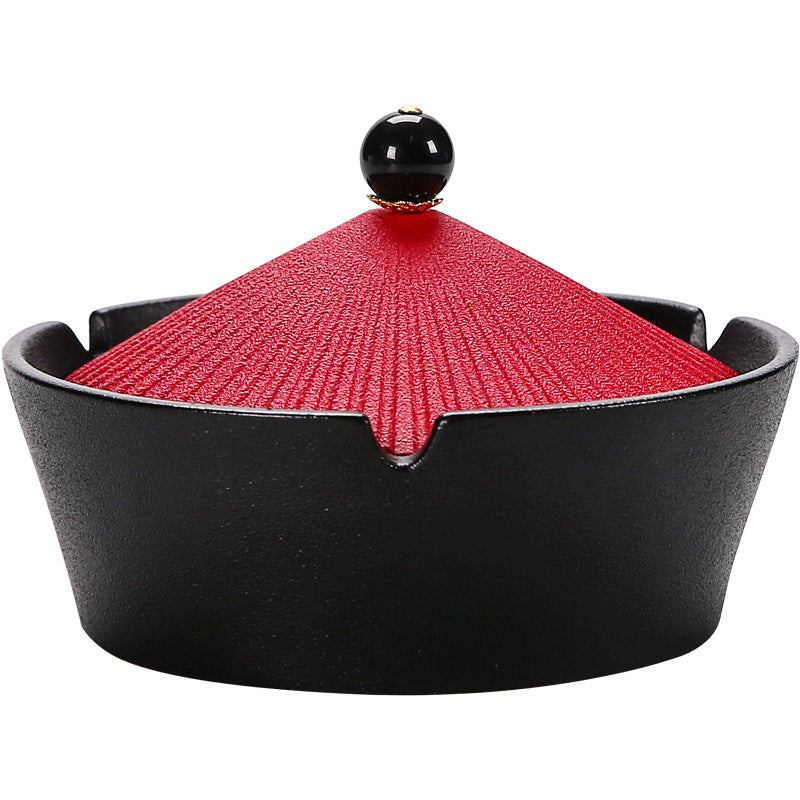 Black ceramic ashtray with a textured red hat-shaped lid