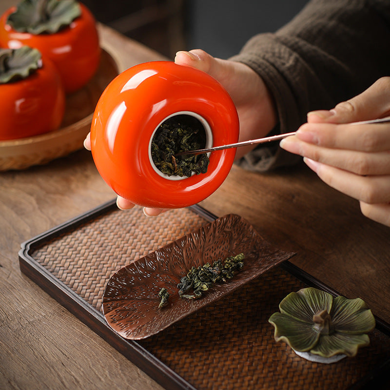 Loose leaf tea being removed from the large persimmon jar