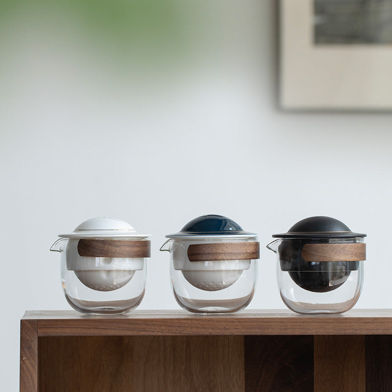 White, blue and black glass tea servers with their pivoting ceramic infusers and domed lids