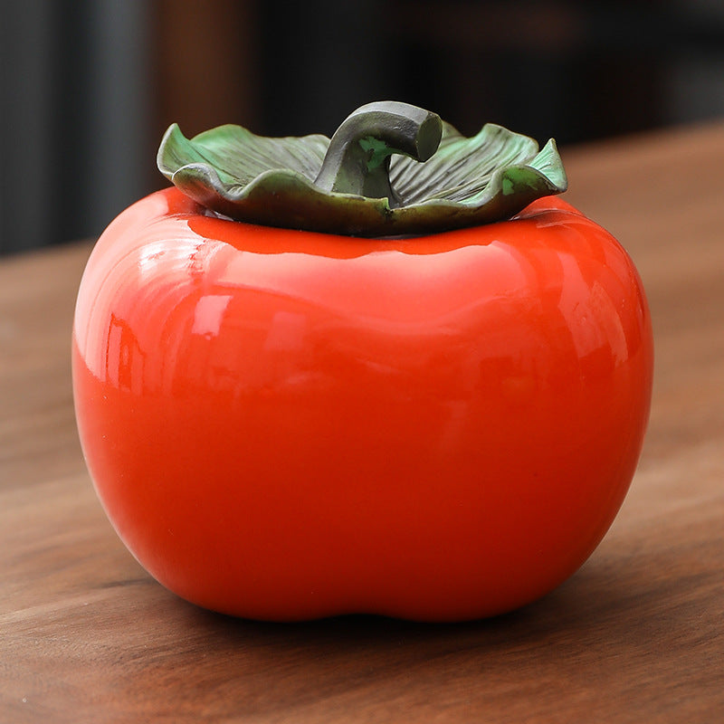 Orange persimmon-shaped ceramic canister with green leaf lid