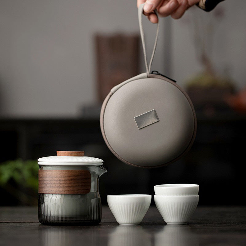 Ribbed glass travel tea pitcher with three white cups and a round carry case