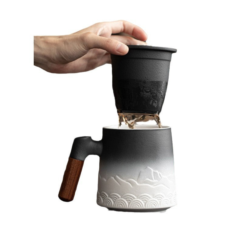 A hand lifting the removable ceramic infuser from the white mountain tea mug