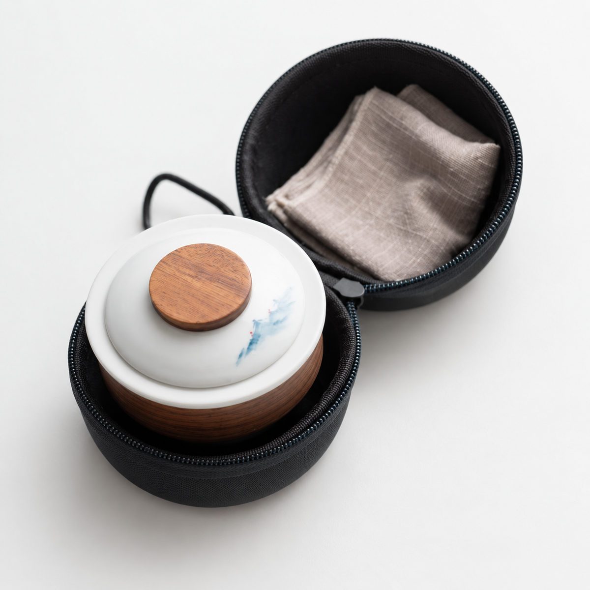 Mountain ceramic lid and nested travel tea set stored inside the open round zip case with a folded cloth
