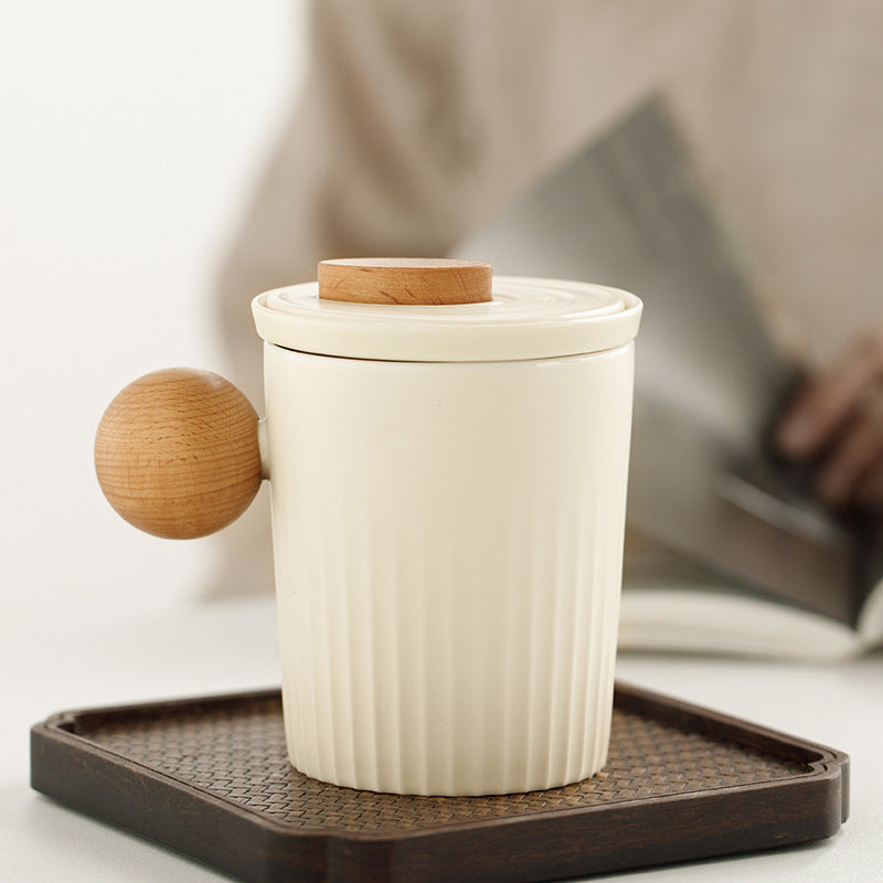 Cream ribbed ceramic tea mug with a wood-look ball handle on a tray
