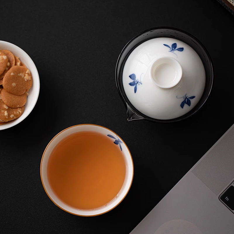 Blue orchid ceramic cup beside a glass brewing pot with a matching lid