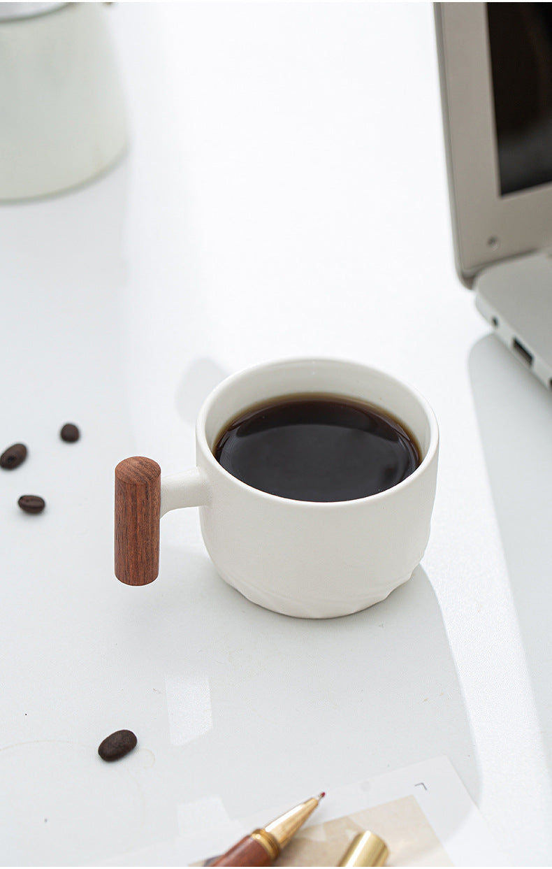 White ceramic wood handle cup filled with coffee on a desk