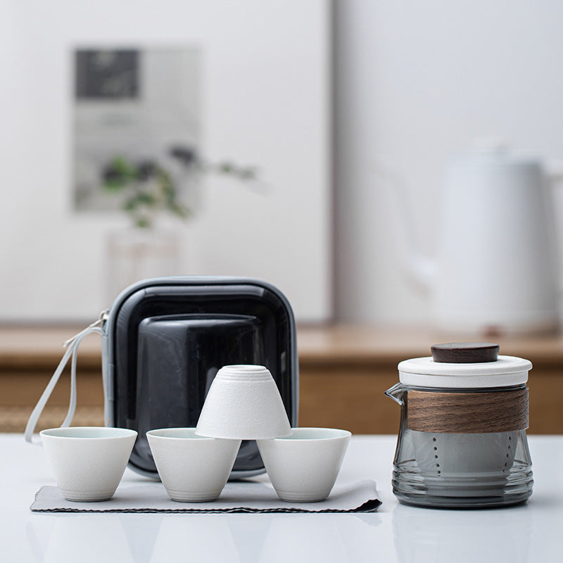 White ceramic travel tea set with smoke-gray glass brewer, four cups and zip case