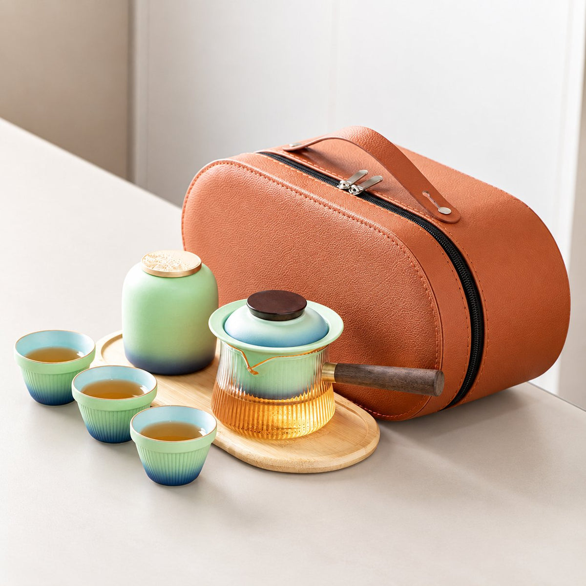 Blue gradient travel tea set with a side-handle glass brewer, three cups, jar, tray and orange case