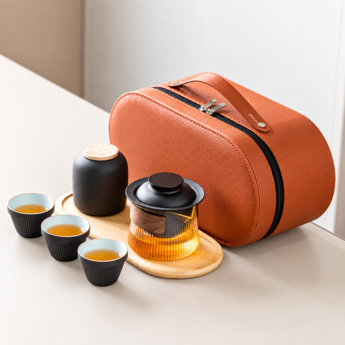 Black travel tea set with a wood-grip glass brewer, three cups, jar, tray and orange case