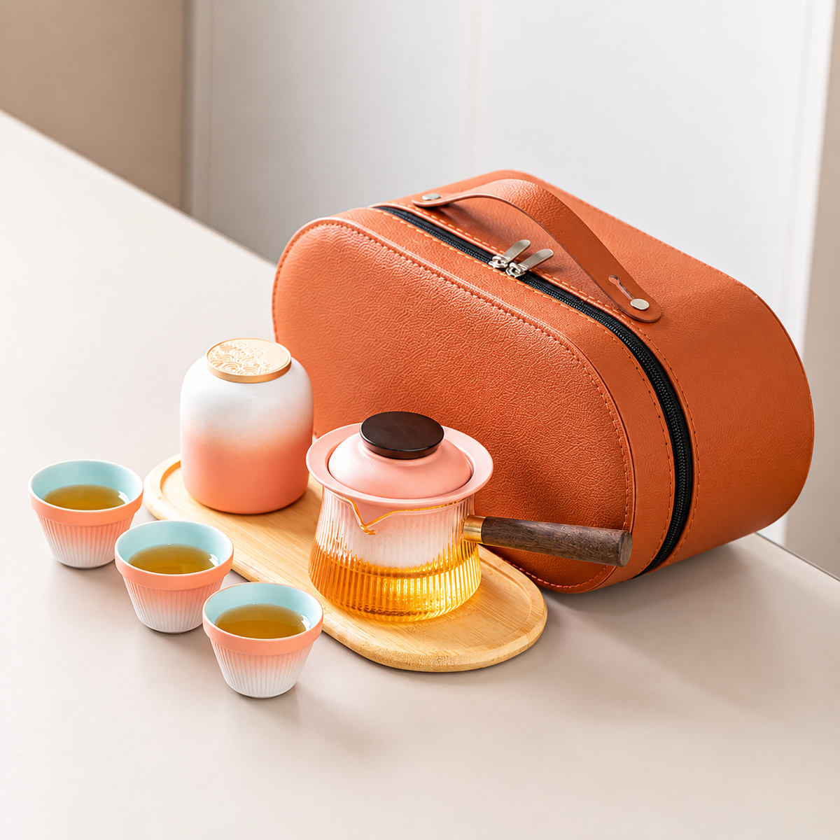 Pink gradient travel tea set with a side-handle glass brewer, three cups, jar, tray and orange case