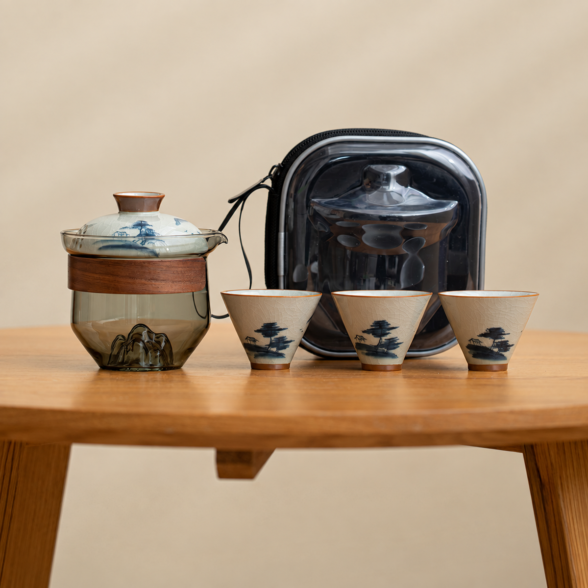 Landscape / Smoke glass tea brewer with three patterned ceramic cups and a black travel case