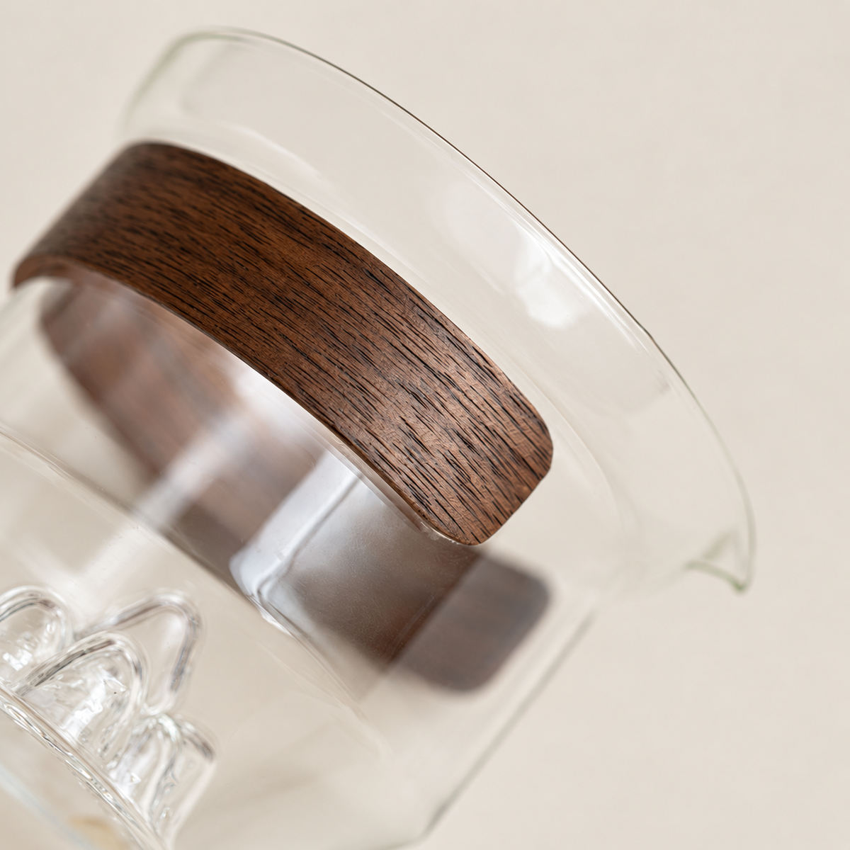 Close view of the wood wrap, glass rim and sculpted base of the tea brewer