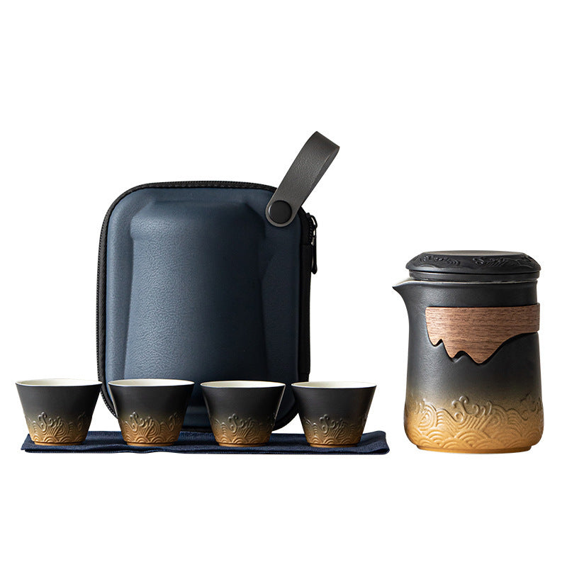 Black and amber wave-relief tea brewer with four cups, cloth and navy carrying case