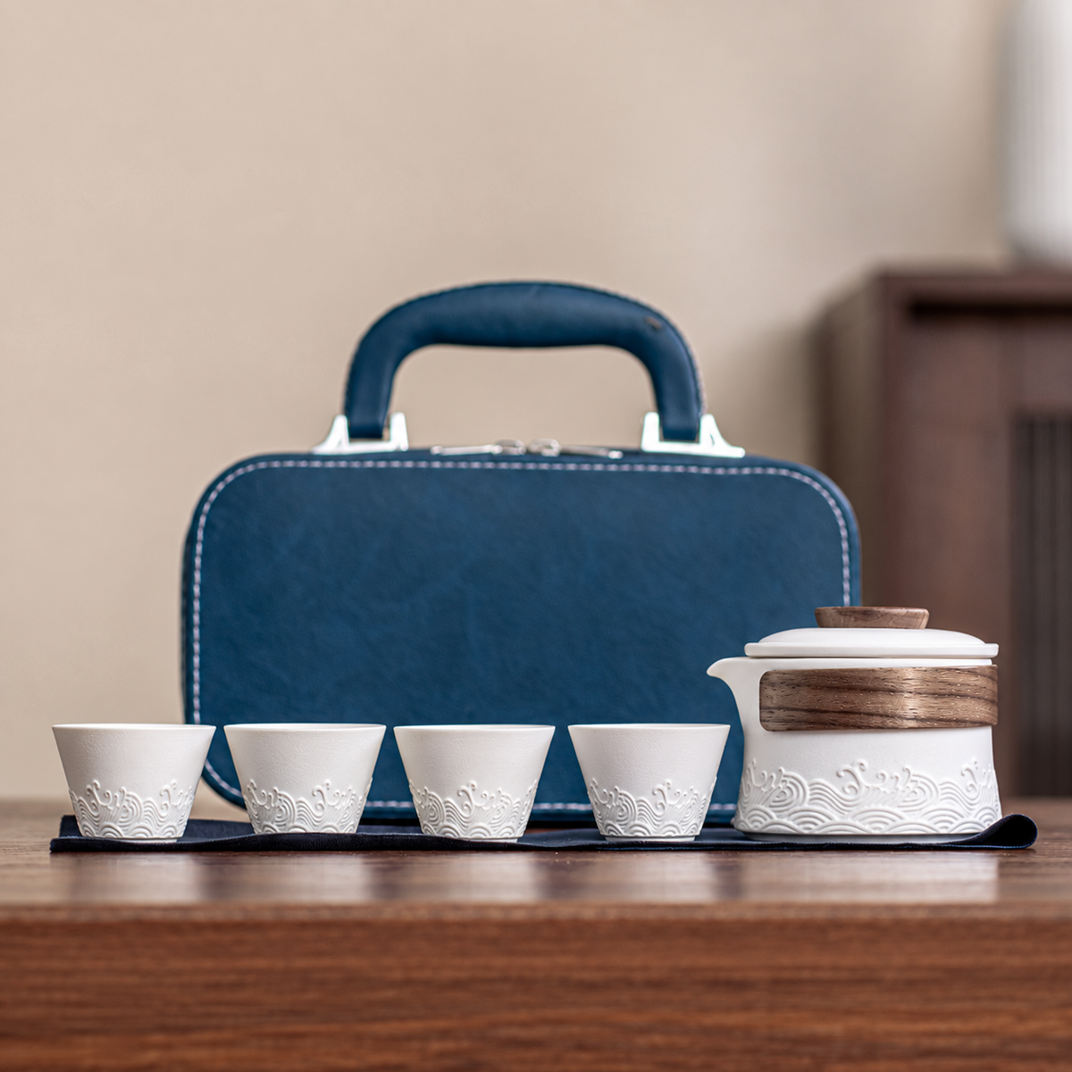 White wave-relief ceramic brewer with four cups and blue carrying case