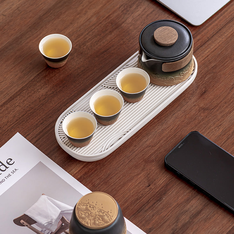 The black and amber four-cup tea set arranged on its oval serving tray