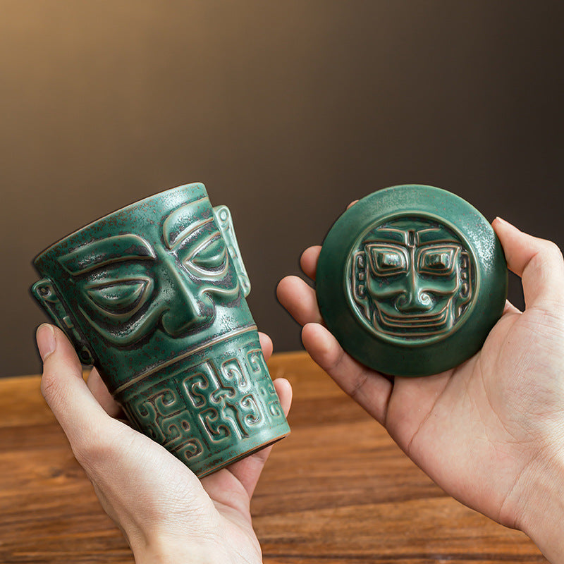 Ceramic mask cup and sculpted matching lid held in hands