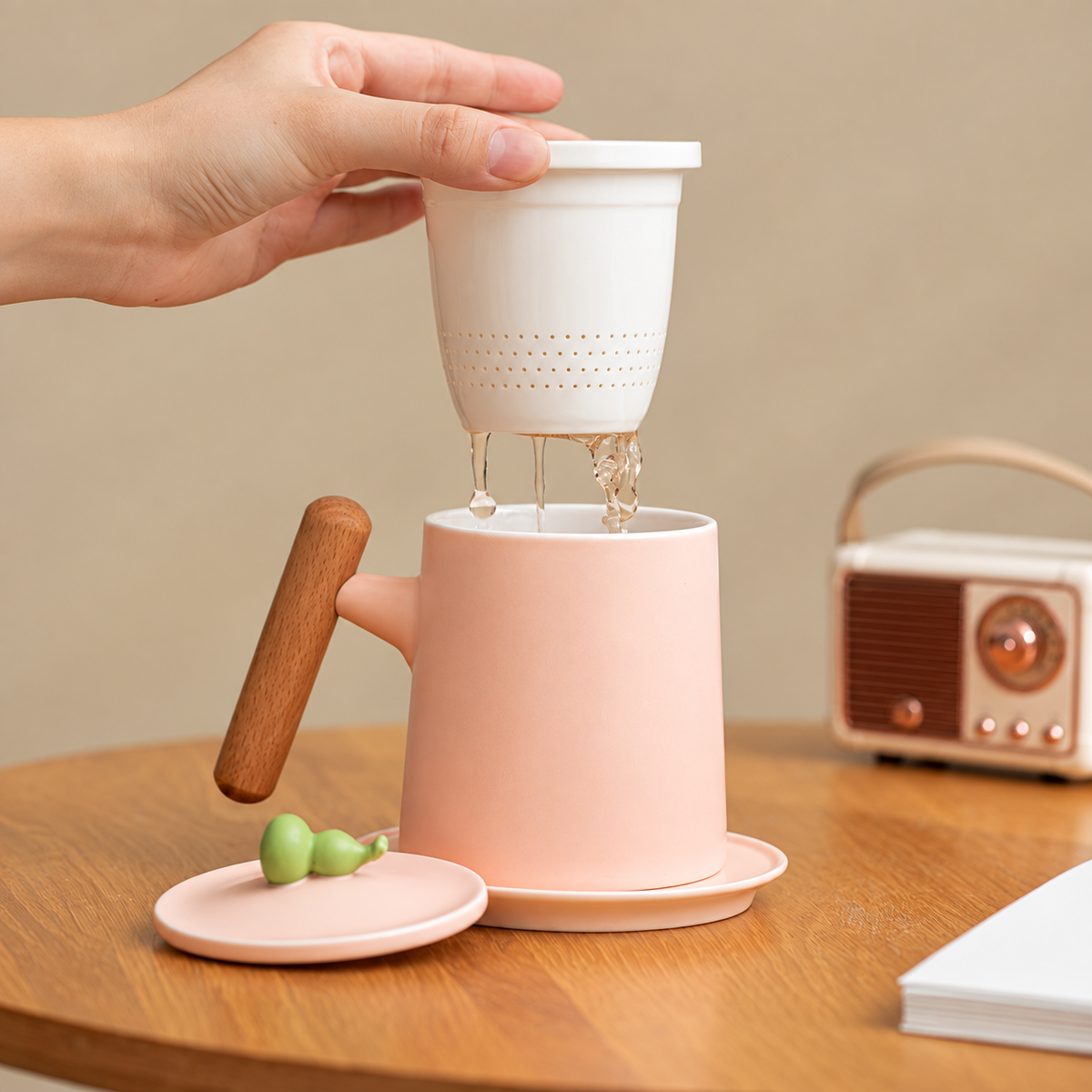 Ceramic infuser lifted from a pink tea mug with a wood grip