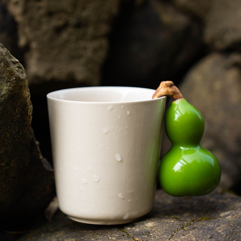 Close view of the green gourd handle and cream glazed mug