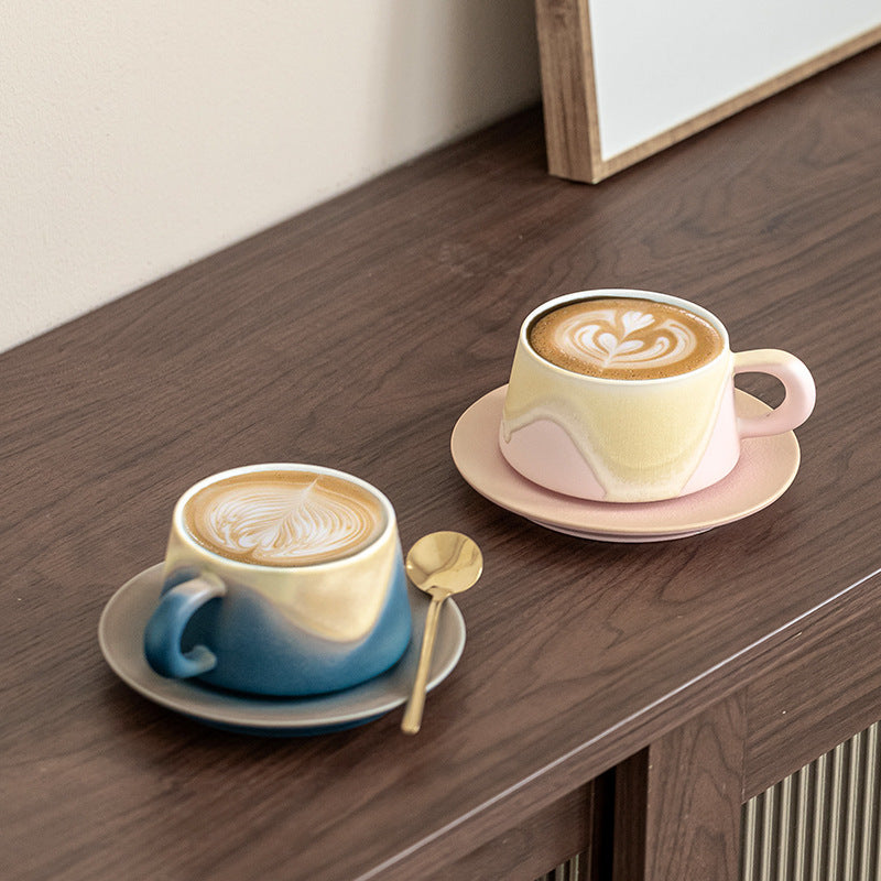 Pink and blue wave-glaze cups filled with coffee, showing their interiors, saucers and handles