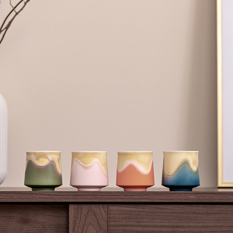 Four ceramic mountain glaze tea cups in green, pink, orange and blue