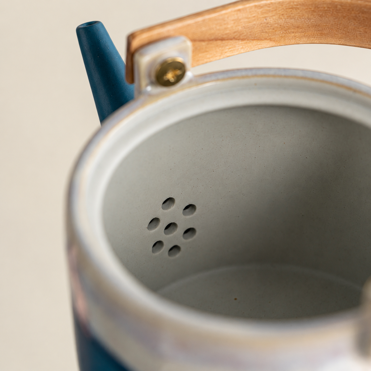 Close-up of the ceramic teapot interior showing the seven filter holes behind the spout