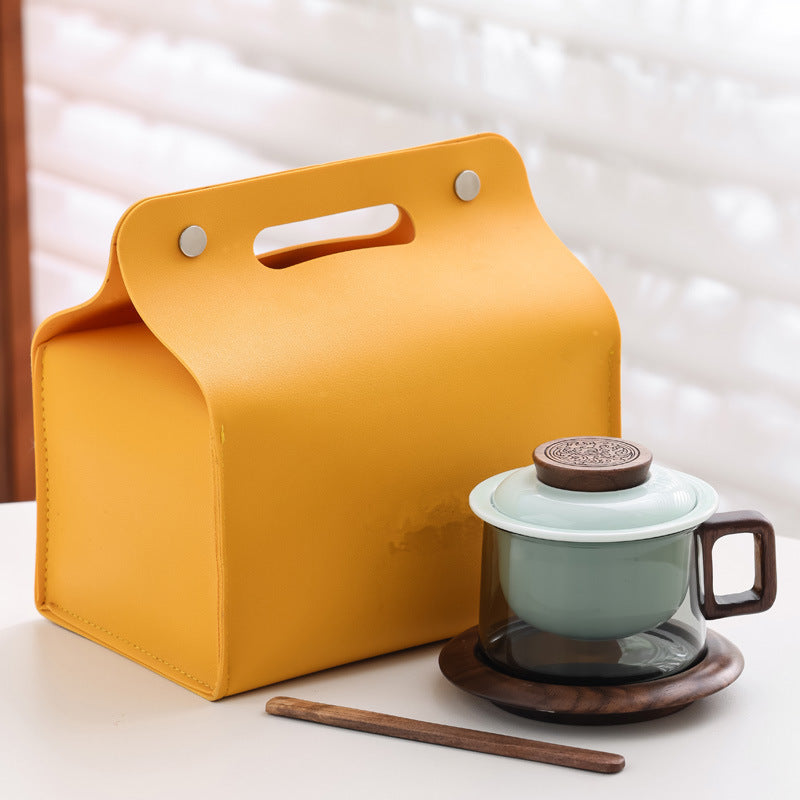 Celadon ceramic infuser and lid in a smoked glass mug with wooden saucer, stirrer and yellow presentation case