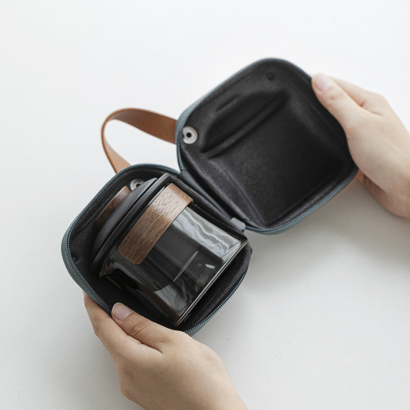 Black ceramic and gray glass brewer packed inside the open blue carrying case, held by hands