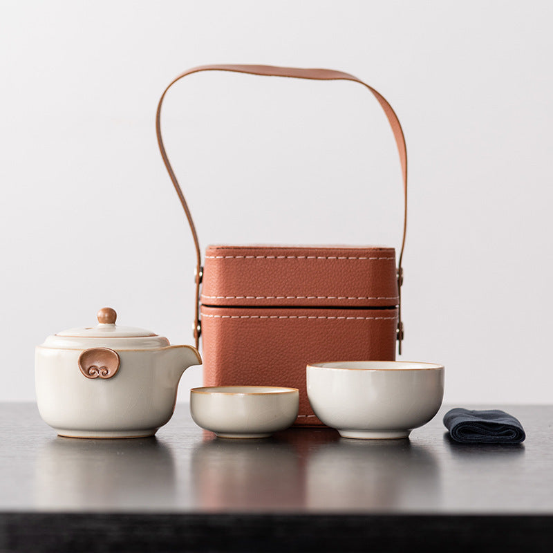 Ivory ceramic travel teapot with two nesting cups, cloth and brown handled case