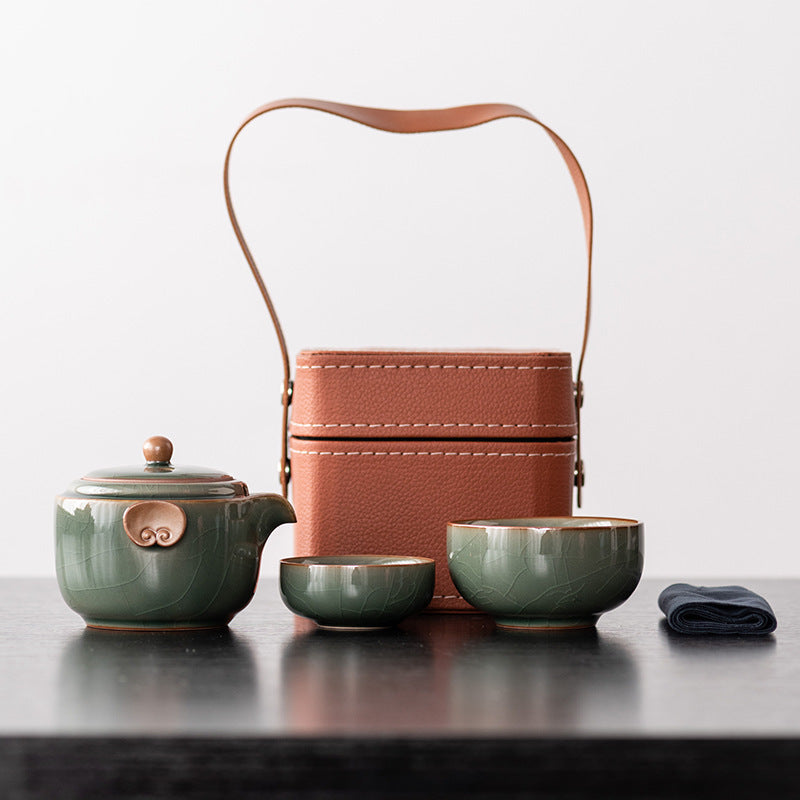 Jade green ceramic travel teapot with two nesting cups, cloth and brown handled case