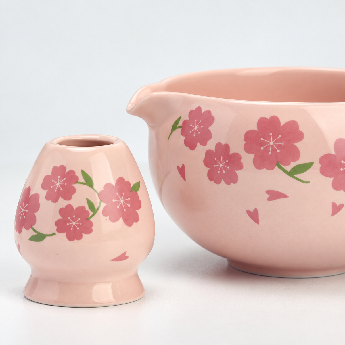 Close detail of pink cherry blossom decoration on the matcha bowl and matching ceramic whisk holder