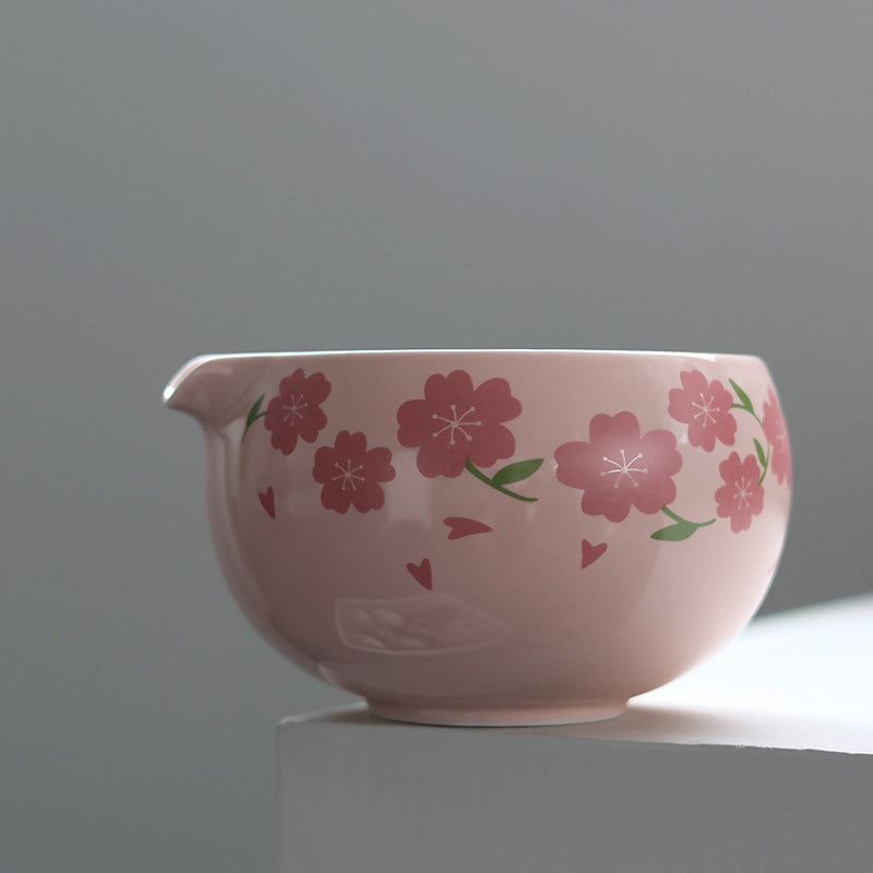 Side profile of the pink blossom matcha bowl showing its pouring spout, flower pattern and foot