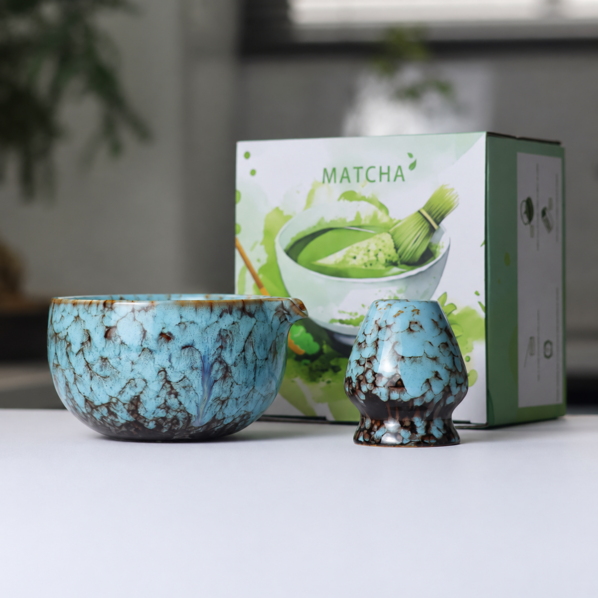 Blue mottled reactive-glaze matcha bowl and whisk holder beside the actual English MATCHA box