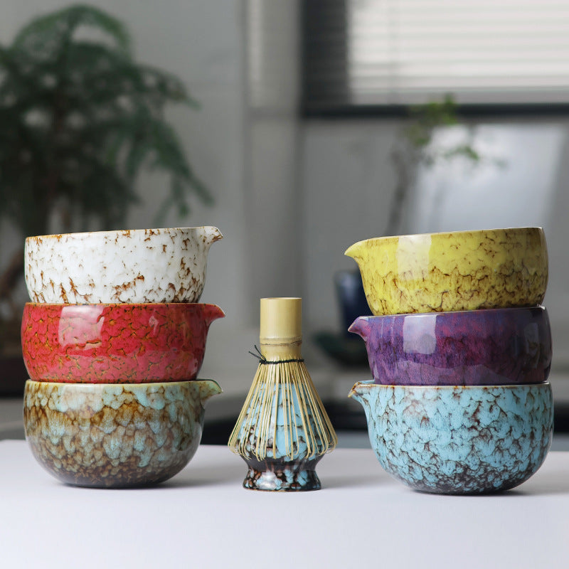 Stacked reactive-glaze bowls with a bamboo whisk resting on the blue holder to demonstrate its shape