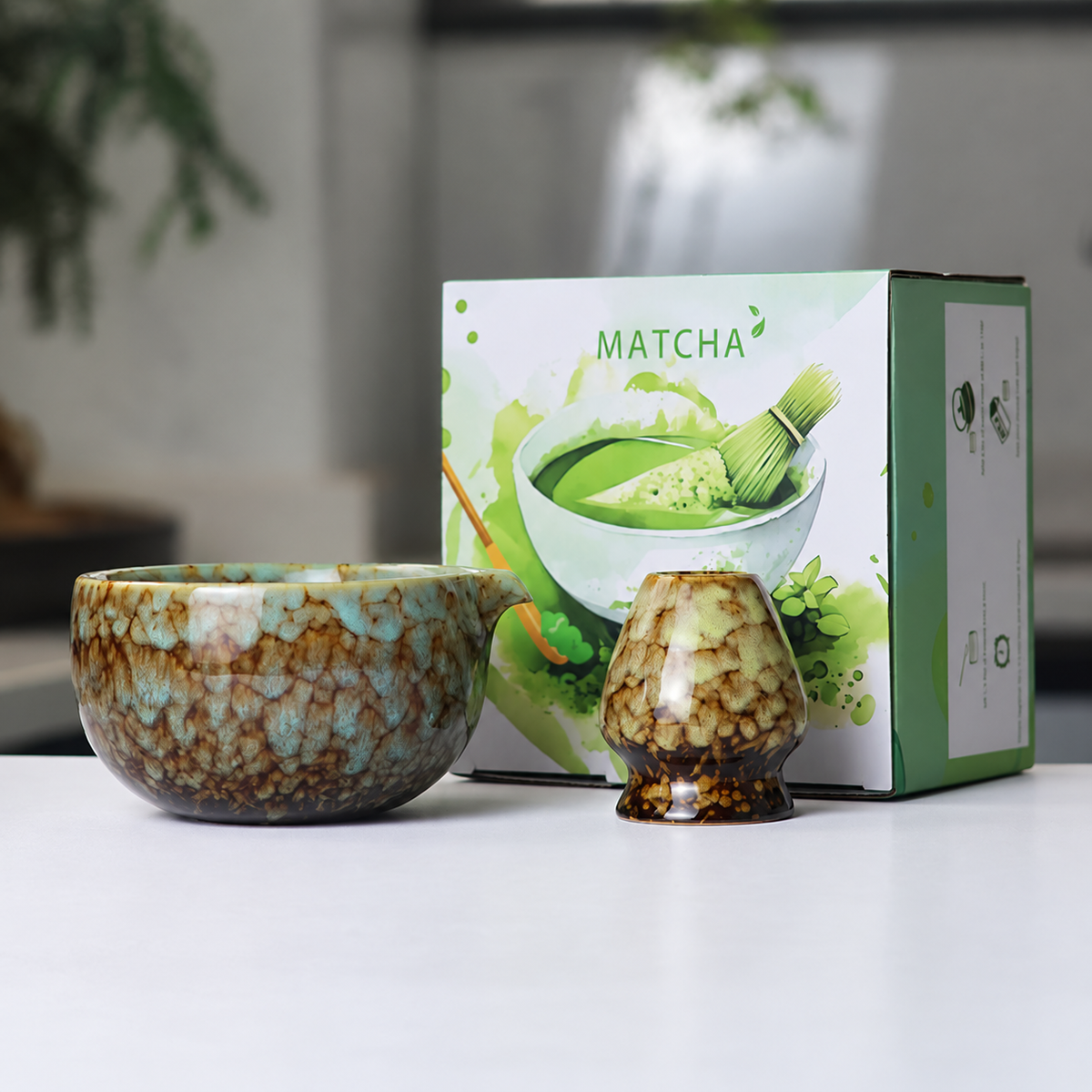 Brown mottled reactive-glaze matcha bowl and whisk holder beside the actual English MATCHA box